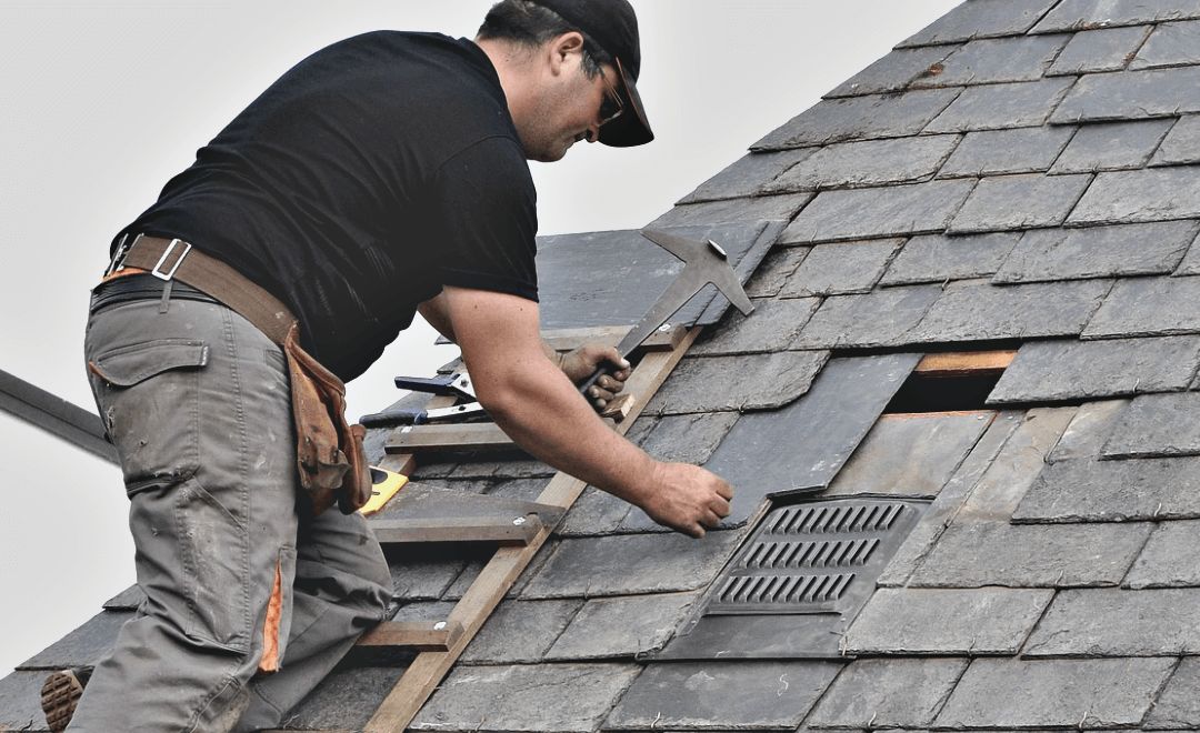 Roofer replacing a damaged section of slate